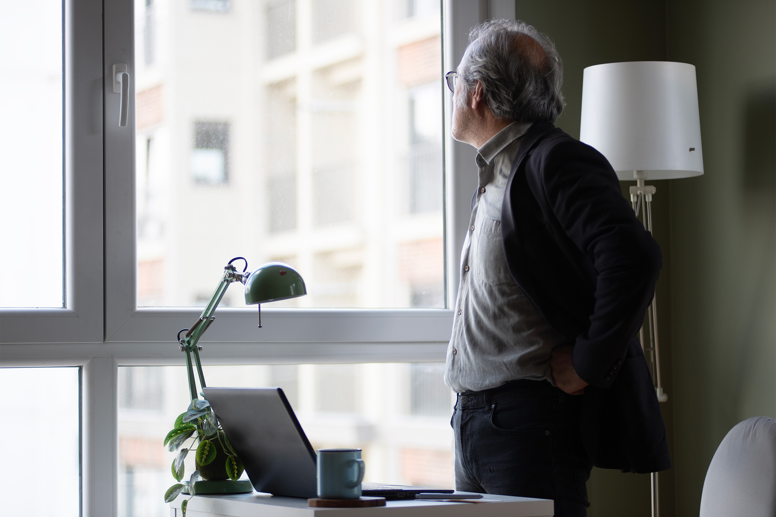 Mann steht nachdenklich am Fenster im Büro